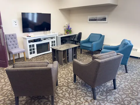 Seating area with armchairs, a television and a bookshelf.