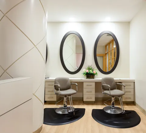 Hair salon with two styling chairs, mirrors and cabinets.