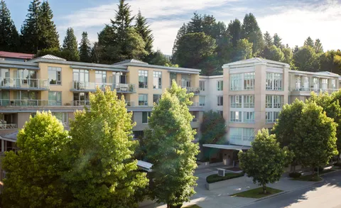 Residence exterior with balconies, trees and a covered entrance.