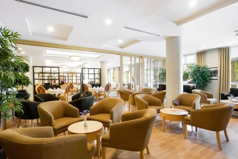 Dining area with tables, upholstered chairs and large windows.