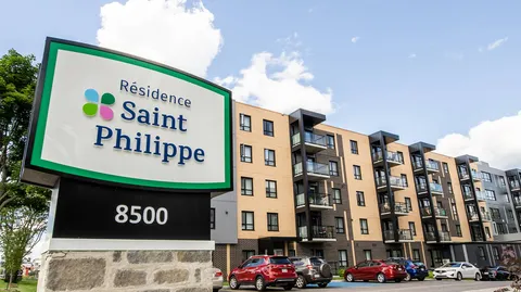 Building with balconies, parked cars and a roadside residence sign