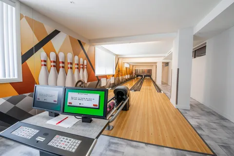 Bowling lanes with score monitors and a wall mural of bowling pins