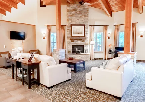 White armchairs around a stone fireplace under a timber ceiling