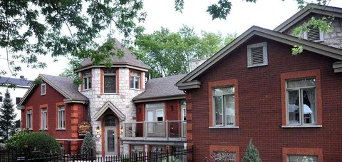 Brick residence with a stone entrance tower and mature trees.