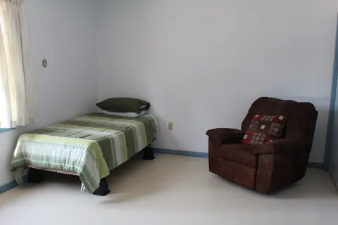 Bedroom with a single bed and upholstered armchair.