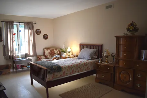 Bedroom with a wooden bed, dresser and sitting area.