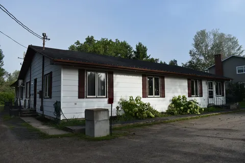 Single-storey residence with white siding beside a paved driveway.