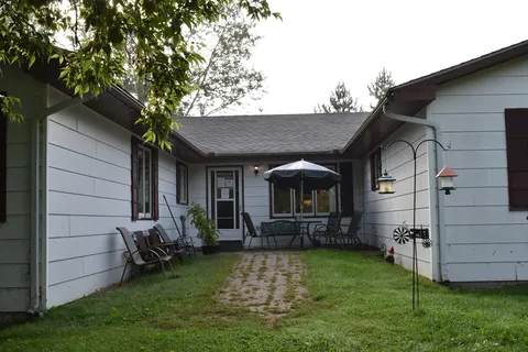 Rear entrance courtyard with a brick path and outdoor chairs.