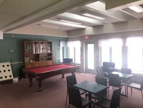 Recreation room with a pool table, chairs and display cabinets.