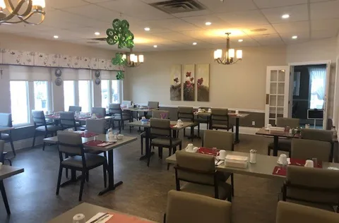 Dining room with set tables, padded chairs and ceiling lights.