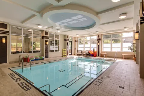 Indoor pool with steps, handrails and large windows