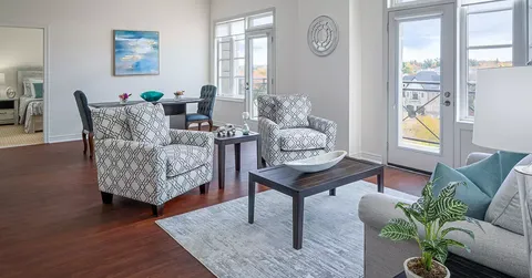 Sitting area with patterned armchairs, a sofa and a table beside a balcony door