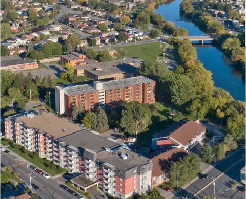 Aerial view of residence buildings beside a river, trees and streets
