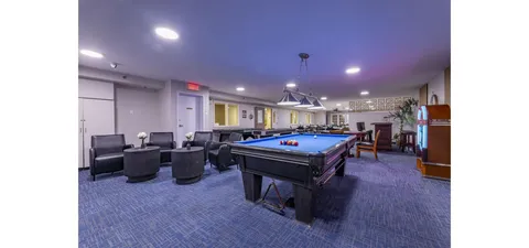 Room with a blue billiard table, armchairs and a pendant light