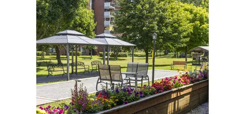 Patio with tables, umbrellas, flower beds and surrounding trees