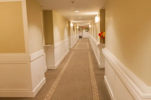 Carpeted corridor with doors and wall lights.