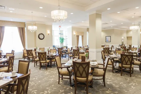 Dining room with set tables, upholstered chairs and chandeliers.