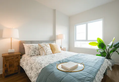 Bedroom with a patterned bedspread, two lamps and a large window