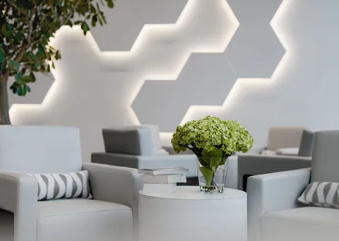Armchairs and tables beside a geometric illuminated wall