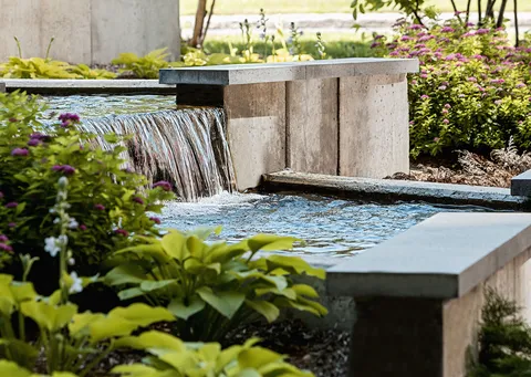 Garden water feature surrounded by flowering plants and lawn