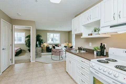 Kitchen with white cupboards opening into a sitting area