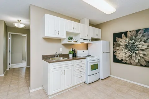 Kitchen with white cupboards, a refrigerator and a stove
