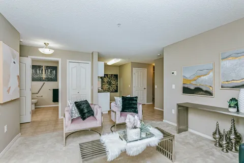 Room with armchairs, a glass table and pale wall art