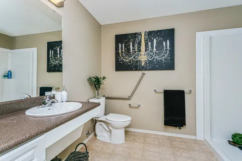 Bathroom with a sink, toilet, mirror and grab bars