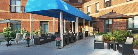 Brick building with a blue entrance canopy beside a furnished patio