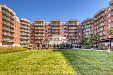 Residence building with balconies surrounding a landscaped courtyard.