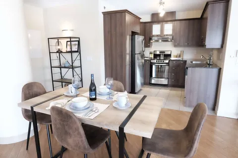 Suite dining table beside a kitchen with wooden cupboards.