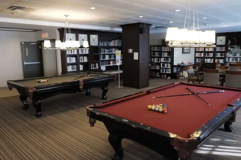 Games room with billiard tables and bookshelves.