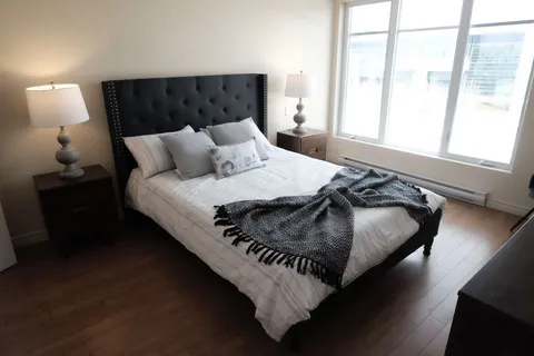 Bedroom with a double bed, bedside lamps and windows.