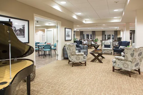 Lobby lounge with armchairs, tables and a grand piano.