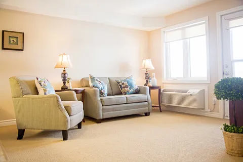 Suite living room with sofa and armchair beside a window.