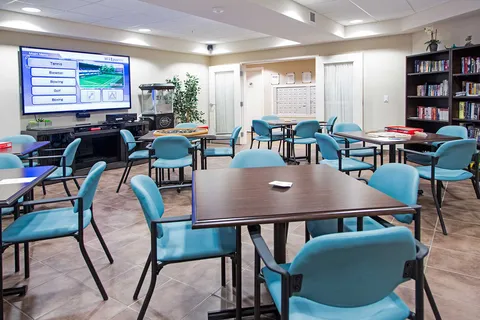Activity room with tables, chairs and bookshelves.