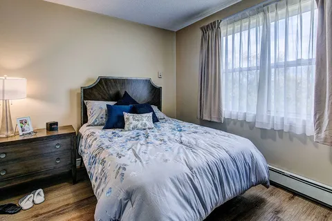 Bedroom with a bed, nightstand and curtained window.