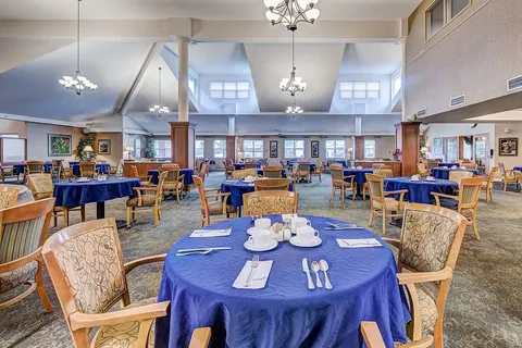 Dining room with round tables, blue tablecloths and chandeliers.