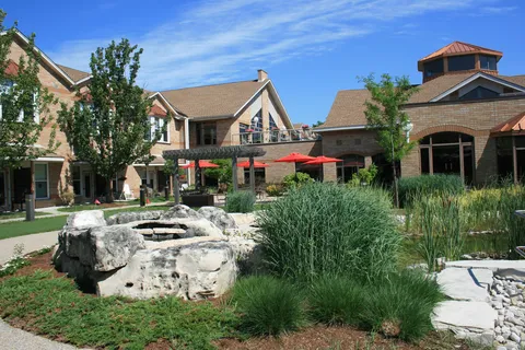 Residence buildings around a landscaped courtyard with rocks, grasses and red umbrellas