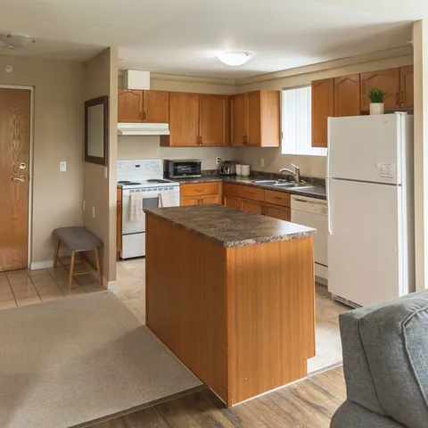 Kitchen with wooden cabinets, an island, white appliances and a sink