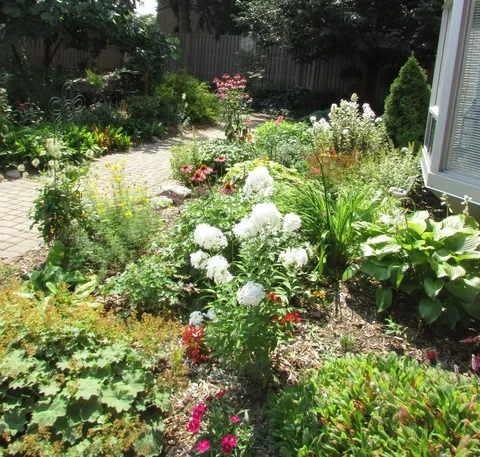 Flower garden beside a brick path and a window