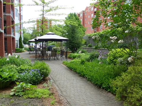 Garden path leading to a gazebo with tables and chairs beside flower beds
