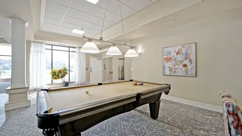 Room with a pool table, cue rack and framed abstract artwork