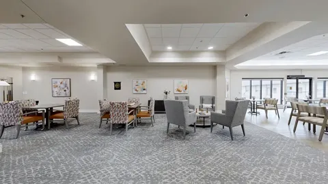 Room with armchairs, round tables and a dartboard