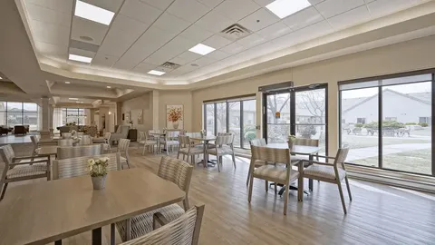 Room with tables and chairs beside large windows