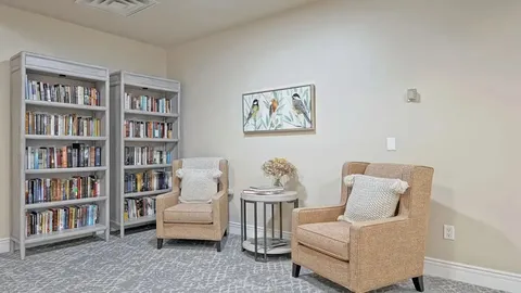 Room with two armchairs, bookshelves and bird artwork