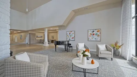 Room with armchairs, a grand piano and framed floral artwork