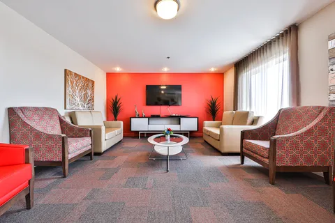 Room with sofas, armchairs and a television on a red wall