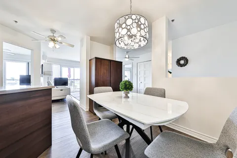 Sitting and dining area with white sofas, a round table and large windows