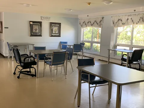 Dining room with rectangular tables, blue chairs and large windows.